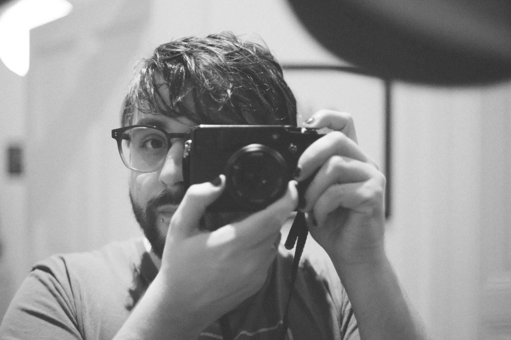 A photograph of me, black and white, holding a camera to my eye